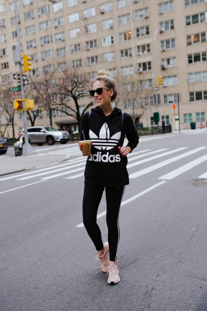 Woman wearing adidas sweatshirt and holding Starbucks coffee