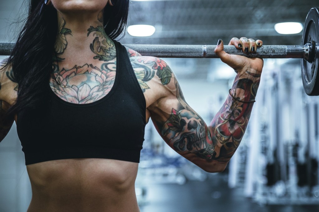 Tattooed fit woman holding barbell