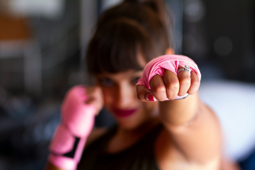 Woman wearing pink boxing gloves and ring 
