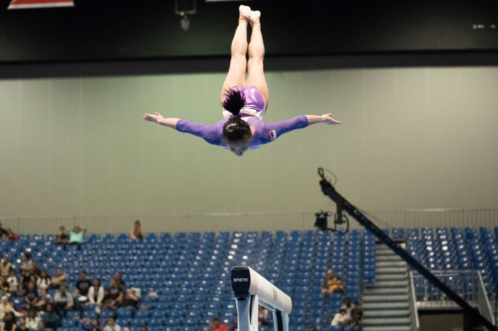 Gymnast wearing purple doing backflip 
