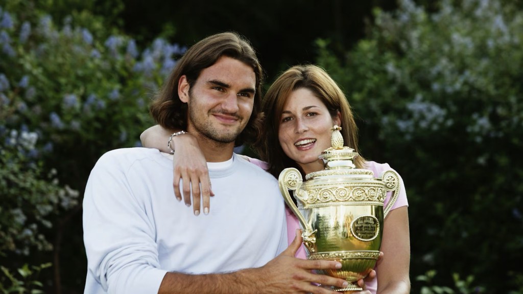 Roger Federer holding trophy with woman next to him 
