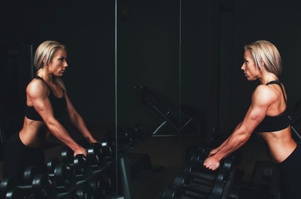 Muscular woman holding dumbbells at gym 